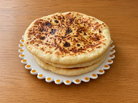 Trois khachapuri imeruli maison empilés sur une assiette, la croûte dorée et tachetée par la cuisson à la poêle